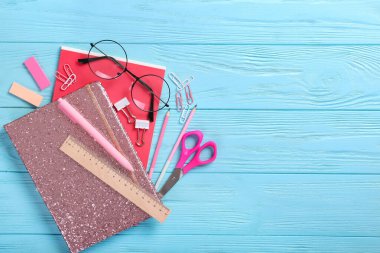 Okul defteri ve mavi ahşap arka planda çeşitli kırtasiye malzemeleri. Eğitim konsepti.