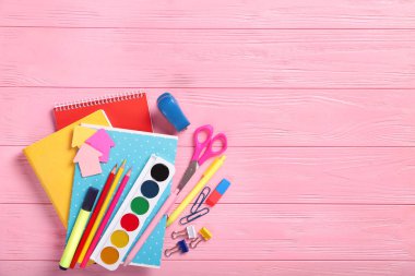 Pembe arka planda parlak okul kırtasiyesi. Üst görünüm, mesaj için yer.