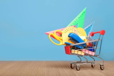 Mavi arka planda kırtasiyeli alışveriş arabası. Metin için yer