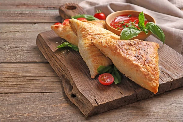 Ahşap arka planda tavuk eti ve soslu leziz samsa.
