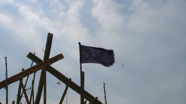 Σχισμένο κουρελιασμένη πειρατής σημαία κύματα του ανέμου που συνδέεται με την νοθεία σε ψηλό πλοίο Dewarcuci όπως σύννεφα περνούν με το μπλε του ουρανού — Αρχείο Βίντεο