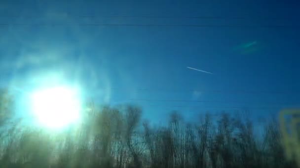 Plano en el cielo contra el telón de fondo del sol de invierno brillante, vista desde el tren — Vídeo de stock