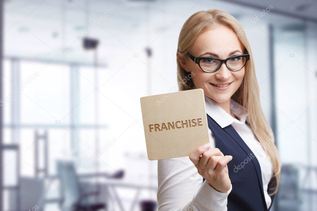 Technology, internet, business and marketing. Young business woman writing word: Franchise