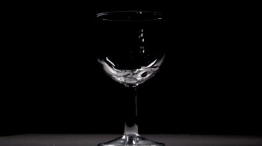 Yavaş çekim siyah arka plan üzerinde şarap cam içine su dökme