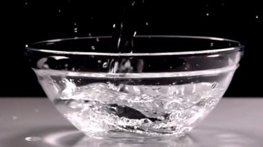 Yavaş çekim siyah arka plan üzerinde şarap cam içine su dökme