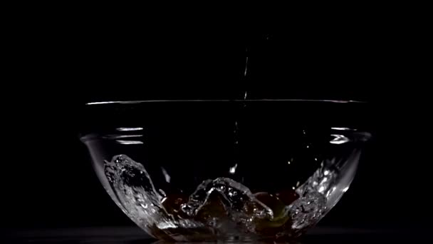 L'eau coule et éclaboussure dans le grand verre à vin avec des raisins au ralenti. Tournage avec caméra haute vitesse .