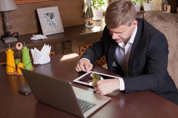 İşadamı kafede otururken tablet üzerinde çalışıyor.