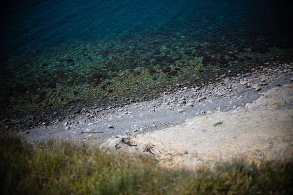 Deniz ve plaja taşlarla altındadır. uçurum izleyen adamım