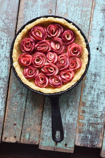 Homemade pastry. Open pie with apple roses in cast iron pan on shabby blue boards copyspace above view