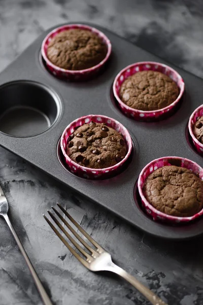 Tasty homemade pastry. Chocolate muffins in baking tin on dark b