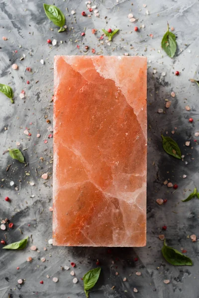Himalayan pink salt block and spices on gray concrete background