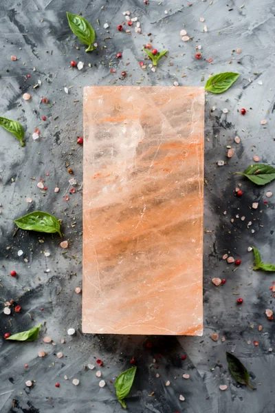 Himalayan pink salt block and crystals on gray concrete backgrou