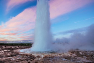 Strokkur şofben Erüpsiyonu İzlanda '. Harika renkler. Mavi gökyüzünde güzel pembe bulutlar.