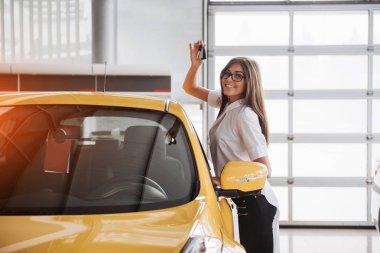 Araba anahtarları gösterilen kameraya bakarak güzel genç bir kadın portresi.