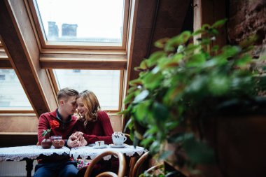 Güzel genç adam ve kadın Sevgililer günü restoranda kutluyoruz. Adam bir gül kız arkadaşına veriyor