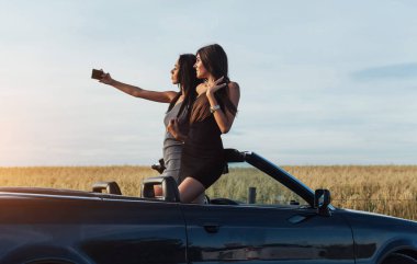 Telefonunuza cabriolet zift ve resimler de yol yakınında duran iki seksi esmer kadın.