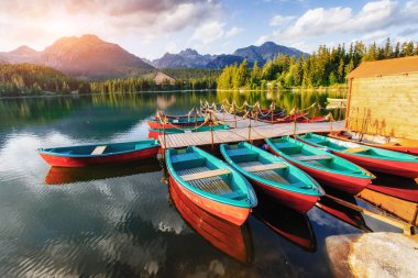 Etrafı dağlarla çevrili günbatımında rıhtım üzerinde tekne. Fantastik Shtrepske Pleso yüksek Tatras. Slovakya, Europe