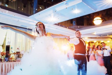 Mutlu gelin ve damat ve ilk dansları, zarif restoranda harika bir ışık ve atmosferi olan düğün.