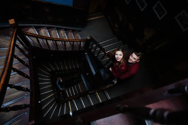 couple of young people on the wooden stairs in the entrance of an old house