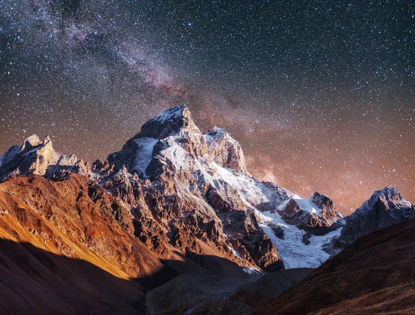 Fantastic starry sky. Autumn landscape and snow-capped peaks. Main Caucasian Ridge. Mountain View from Mount Ushba Meyer, Georgia. Europe.