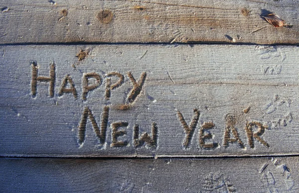 Writing on the snow. Wooden texture. On a wooden board. Happy New Year.