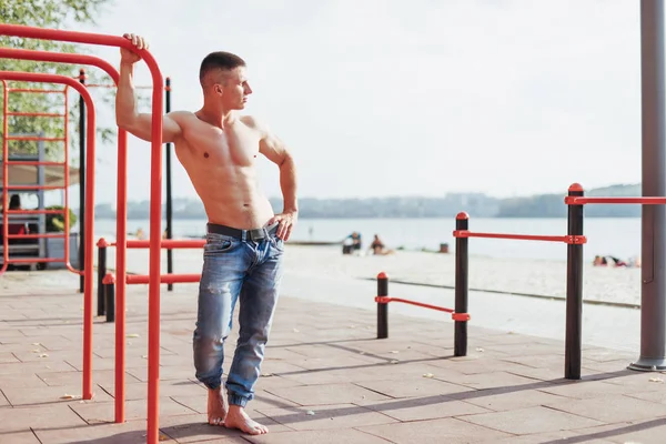 Güçlü genç atlet parkta nişanlı. Açık havada çubuklarındaki egzersizleri. Fitness. Spor. Egzersizleri.