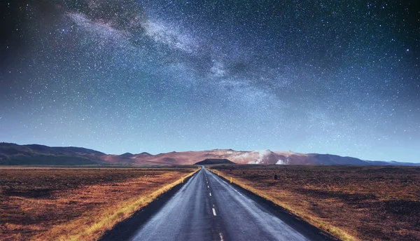 stock image Starry Sky over the mountains. The asphalt road with white markings. Beautiful summer landscape. Soft filtering effect. Iceland.