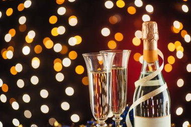 Şampanya ile Noel ve yeni yıl kutlama. Flüt ve şişe şampanya altın parıltılı ışık ve bokeh karanlık bir arka plan karşı şenlikli günler için çift