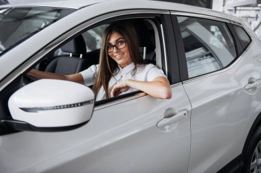 Arabanın ön koltuğunda kameraya bakarak çekici genç beyaz bir kadın