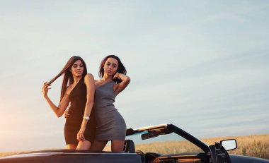 Yol kenarındaki yollarda siyah bir arabada iki kadın.