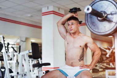 Güzel atletik vücut geliştirmeci adam, egzersiz spor salonunda dumbbells ile gerçekleştirdiği. Spor. Fitness.