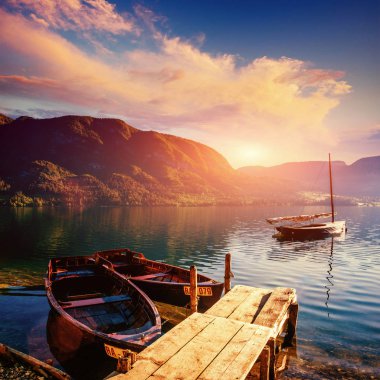 Dağlar ve deniz araçları için önde gelen ahşap duvar arasında bir gölde fantastik günbatımı.