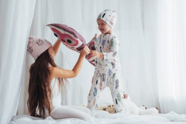 Yumuşak sıcak pijama yatakta oynayan çocuklar