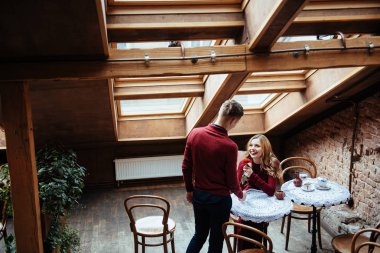 Güzel genç adam ve kadın Sevgililer günü restoranda kutluyoruz. Adam bir gül kız arkadaşına veriyor