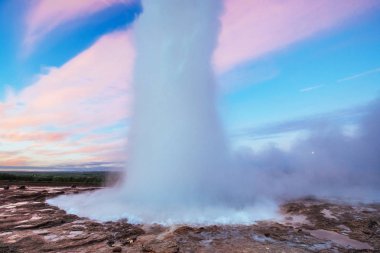 Strokkur şofben Erüpsiyonu İzlanda '. Harika renkler. Mavi gökyüzünde güzel pembe bulutlar.