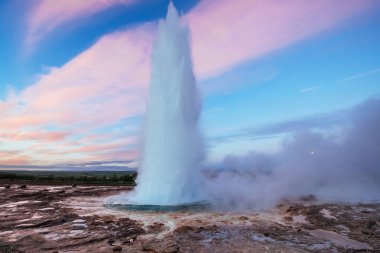 Strokkur şofben Erüpsiyonu İzlanda '. Harika renkler. Mavi gökyüzünde güzel pembe bulutlar.