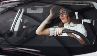Arabanın ön koltuğunda kameraya bakarak çekici genç beyaz bir kadın