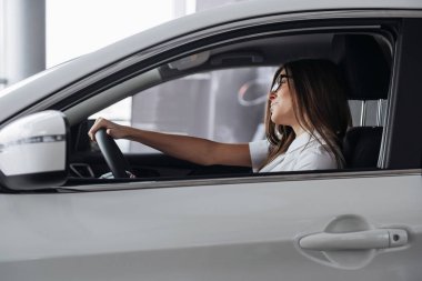 Arabanın ön koltuğunda kameraya bakarak çekici genç beyaz bir kadın