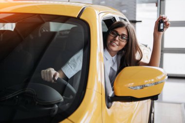 Yeni araba anahtarları gösterilen gülümseyen kadın sürücü.