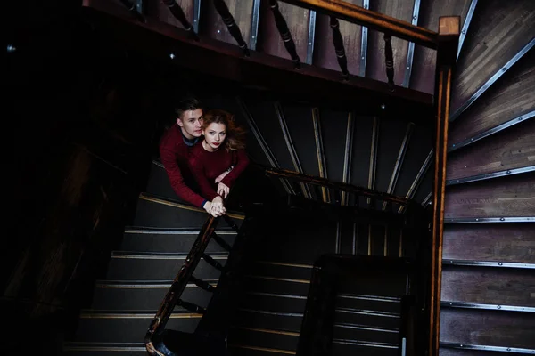 couple of young people on the wooden stairs in the entrance of an old house