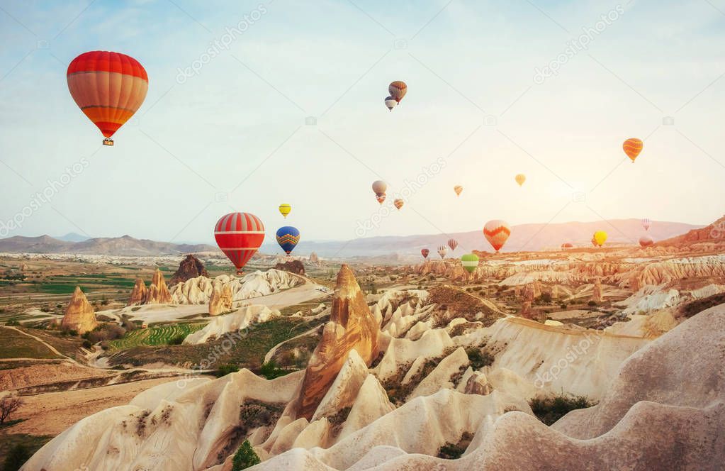 Colorful hot air balloons flying over Red valley at Cappadocia, Anatolia, Turkey. Volcanic mountains in Goreme national park.