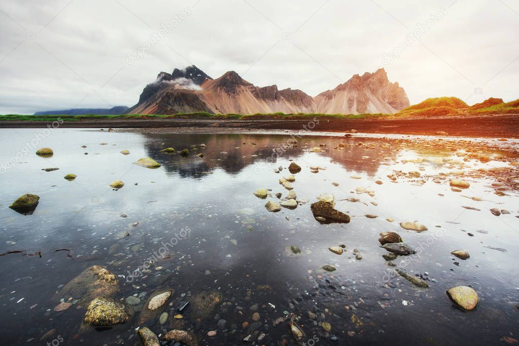Amazing mountains reflected in the water at sunset. Stoksnes, Iceland.