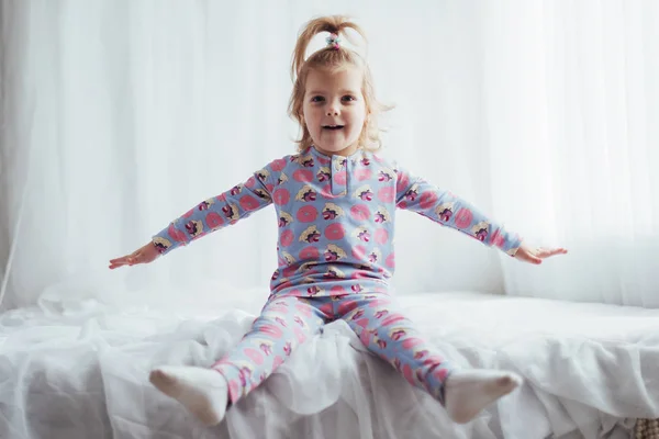 ベッドで遊ぶソフト暖かいパジャマの子 — ストック写真