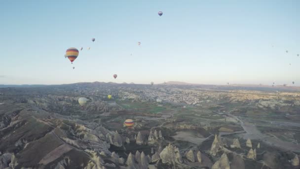 Bunte Heißluftballons fliegen über dem Tal in Goreme, Türkei. Touristen aus aller Welt kommen nach Kappadokien, um eine Reise in einem Heißluftballon zu unternehmen — Stockvideo