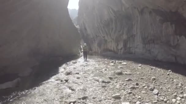 Fotograaf tussen hoge kliffen boven op een berg rivier wandelen — Stockvideo