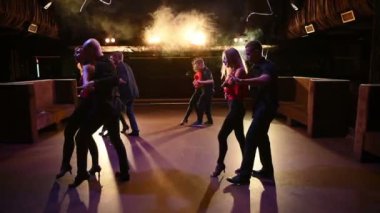 Genç enerjik çekici çiftler akşam vakti açık hava partisinde salsa, bachata, latin dansı yapıyorlar..