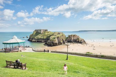Tenby, Galler - 12 Ağustos 2017: Tenby kale kalıntıları ve kumlu plaj onların zaman zevk insanlar Tenby, Galler yaz aylarında düşük tide görüş.