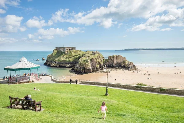 Tenby, Galler - 12 Ağustos 2017: Tenby kale kalıntıları ve kumlu plaj onların zaman zevk insanlar Tenby, Galler yaz aylarında düşük tide görüş.