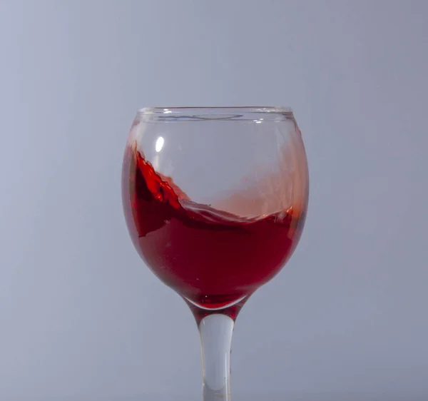 Rotweinspritzer im Glas auf weißem Hintergrund — Stockfoto