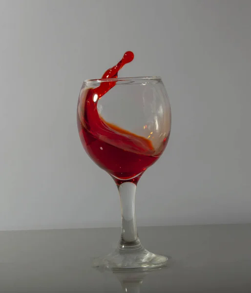 Брызги красного вина в стакане на белом фоне — стоковое фото